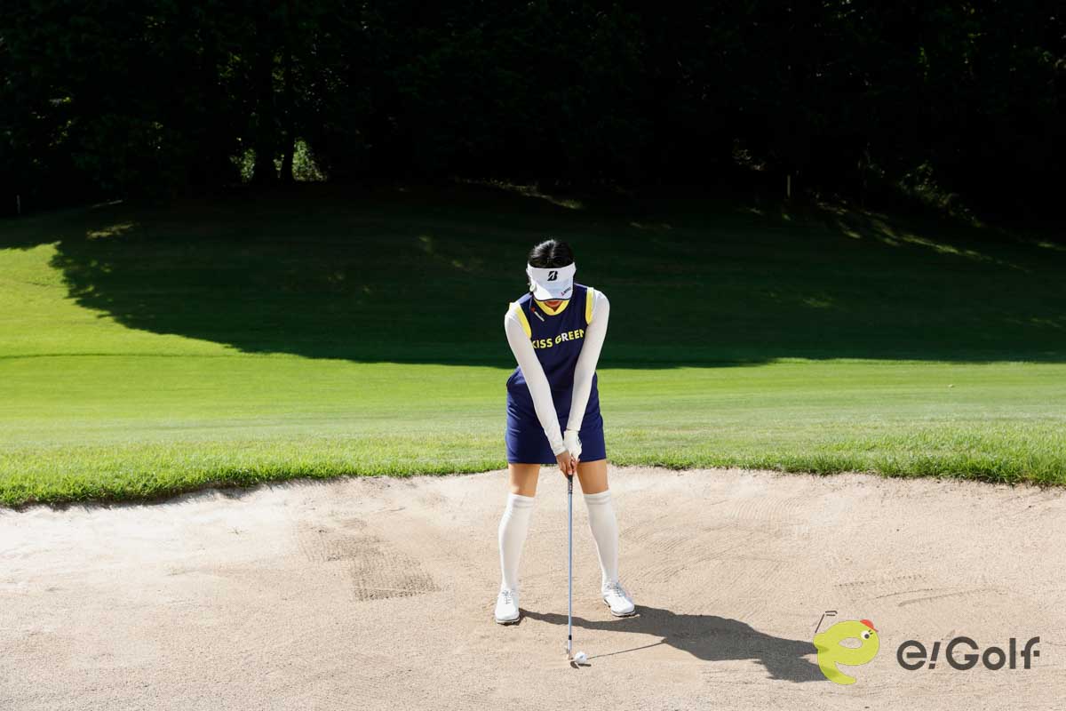 クラブを短く持ち、足を砂に埋めずにアドレス。いつもよりボール一個ぶん右足寄りにボールをセットして、いつもどおりのスイングする