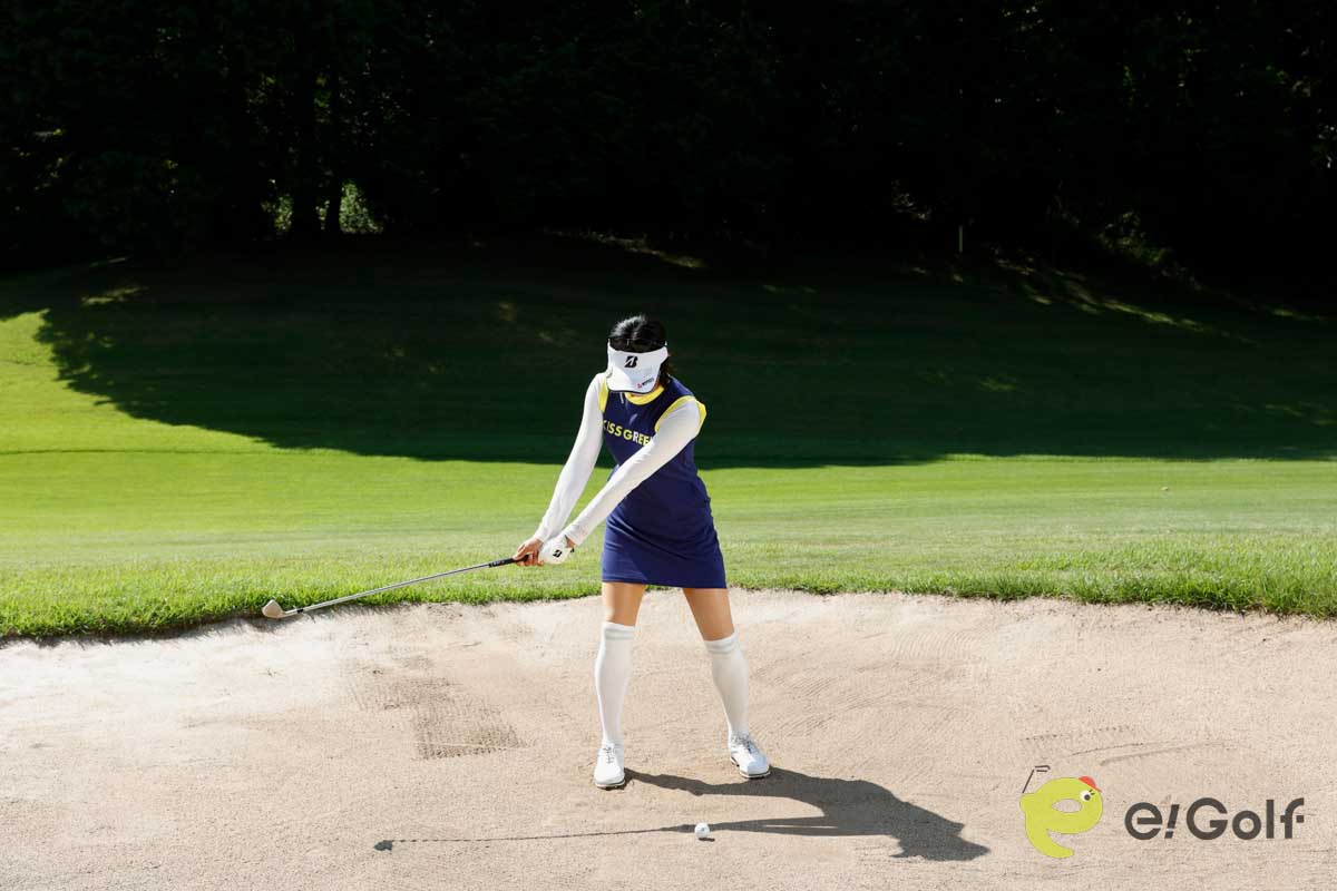 クラブを短く持ち、足を砂に埋めずにアドレス。いつもよりボール一個ぶん右足寄りにボールをセットして、いつもどおりのスイングする