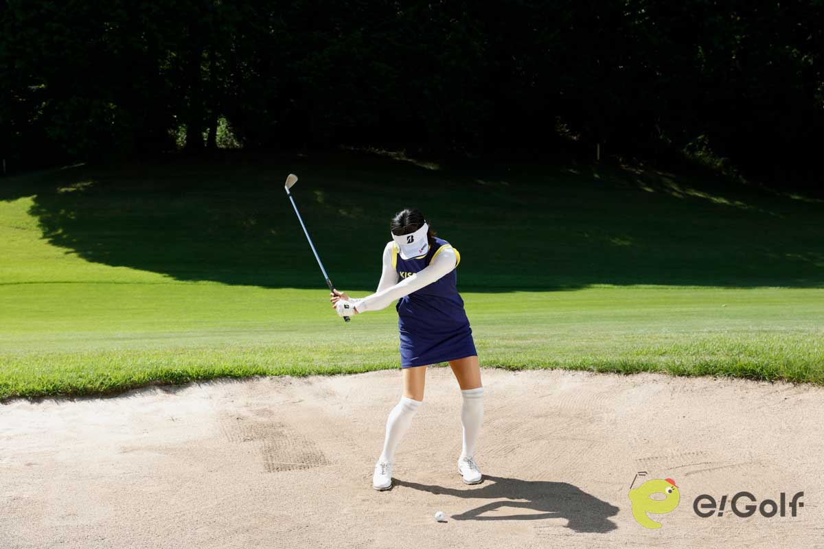 クラブを短く持ち、足を砂に埋めずにアドレス。いつもよりボール一個ぶん右足寄りにボールをセットして、いつもどおりのスイングする