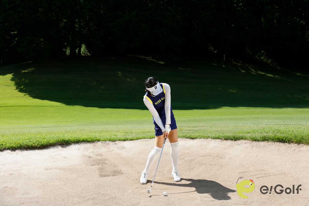 クラブを短く持ち、足を砂に埋めずにアドレス。いつもよりボール一個ぶん右足寄りにボールをセットして、いつもどおりのスイングする