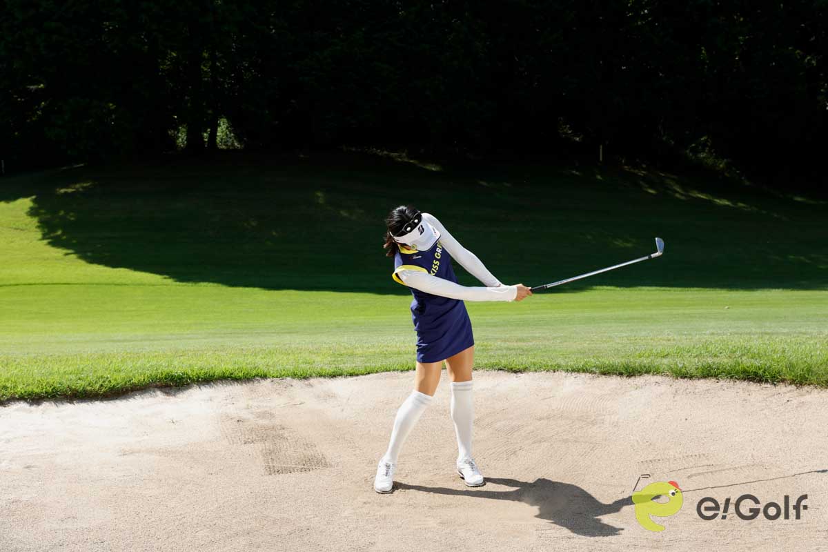 クラブを短く持ち、足を砂に埋めずにアドレス。いつもよりボール一個ぶん右足寄りにボールをセットして、いつもどおりのスイングする