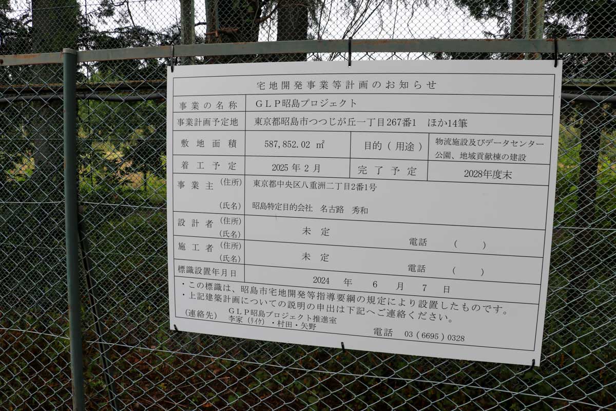 昭和の森跡地外周の金網に掲げられた「宅地開発事業等のお知らせ」。「物流施設及びデータセンター 公園、地域貢献棟の建設」とある 写真:清流舎