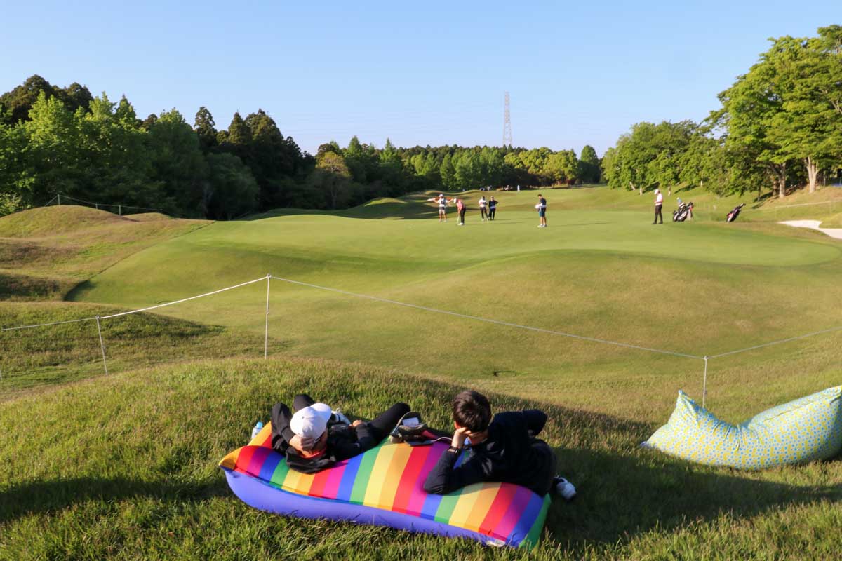 9番グリーン奥で寝そべり、リラックスして観戦するギャラリーたち　写真：清流舎