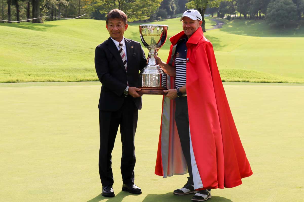 特製のガウンを羽織ったイエーツに、優勝カップを贈った明神PGA会長　写真：清流舎
