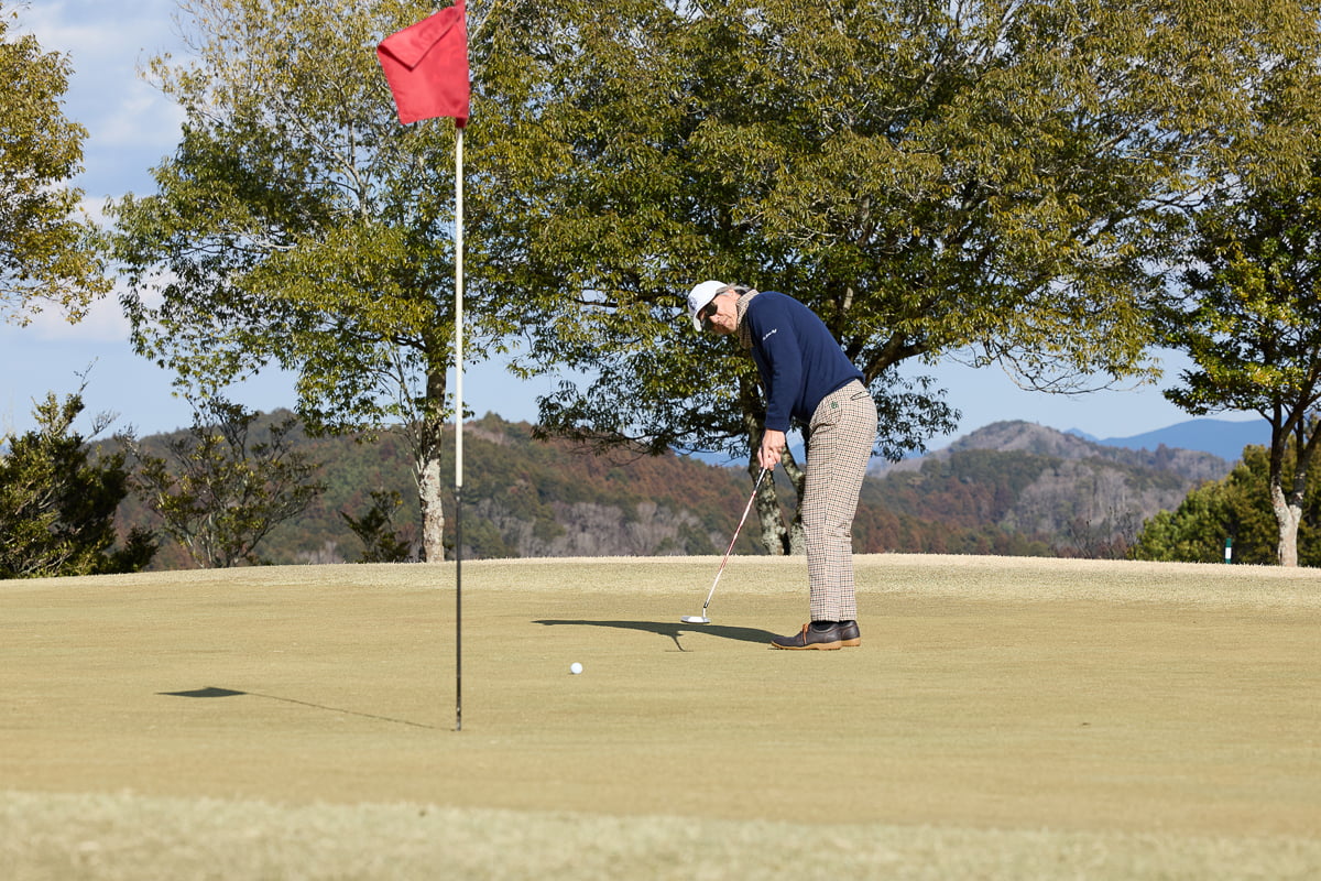グリーンの傾斜を読み、パッティングをする筆者（九島辰也）。自然に囲まれた丘陵コースでのゴルフを満喫した[写真：望月浩彦]
