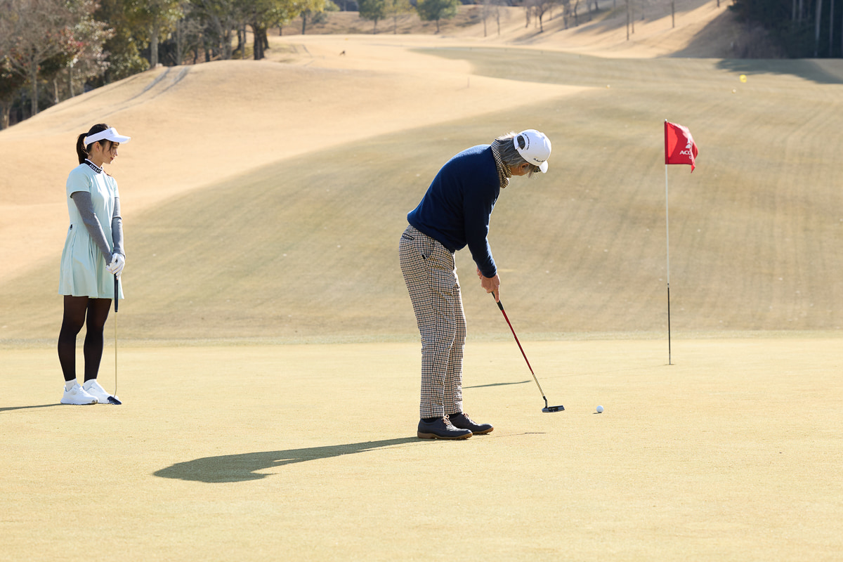 グリーンの傾斜を読み、パッティングをする筆者（九島辰也）。自然に囲まれた丘陵コースでのゴルフを満喫した[写真：望月浩彦]